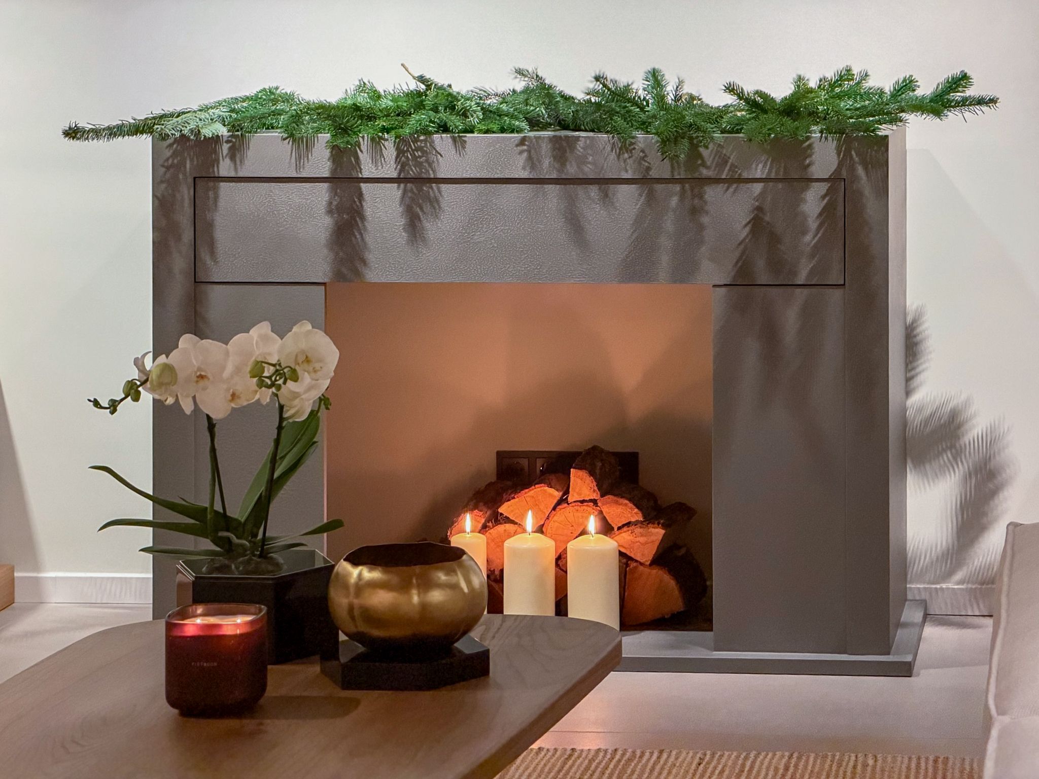 Kamin mit Kerzen, Orchideen und frischem Grün
