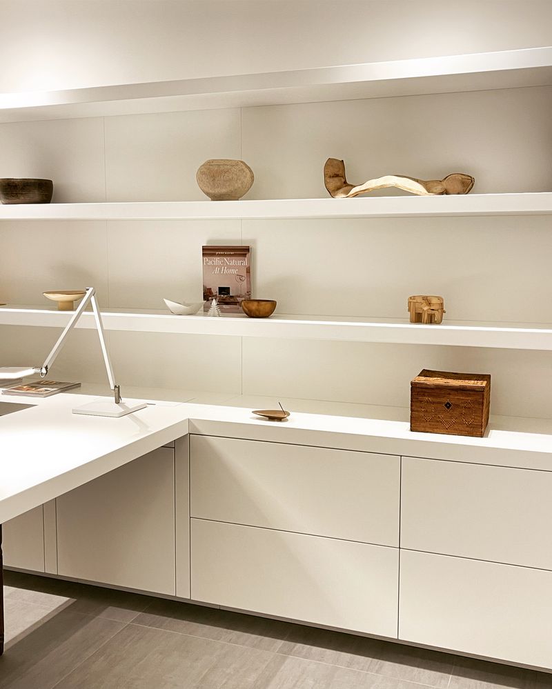Weiße Regalwand mit Fundstücken aus Holz über einem Schreibtisch